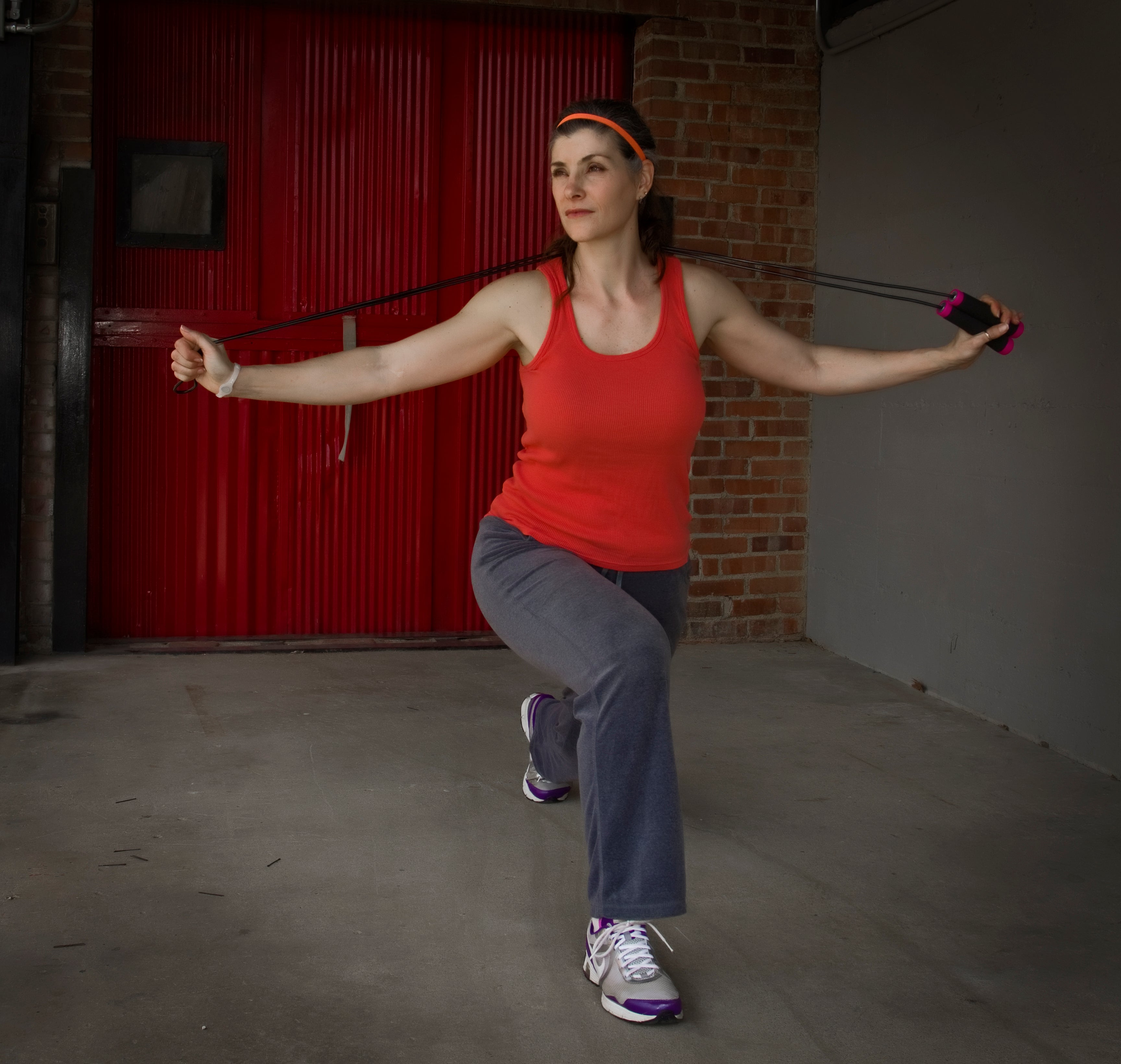 Woman exercising with resistance bands in a garage setting, wearing concealed carry holster
